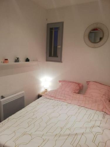 une chambre avec un grand lit avec des oreillers roses dans l'établissement Joli appartement climatisé proche plage et port, à Sanary-sur-Mer