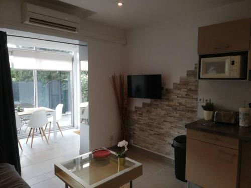 a kitchen and living room with a table and a tv at Joli appartement climatisé proche plage et port in Sanary-sur-Mer