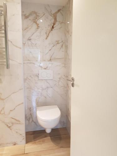 La salle de bains est pourvue de toilettes blanches et de murs en marbre. dans l'établissement Dishoek, à Dishoek