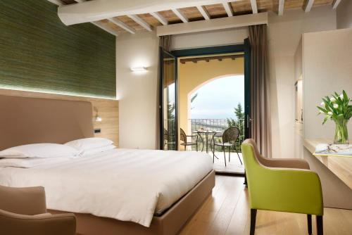 a bedroom with a large bed and a balcony at Borgobrufa Spa Resort Adults Only in Brufa