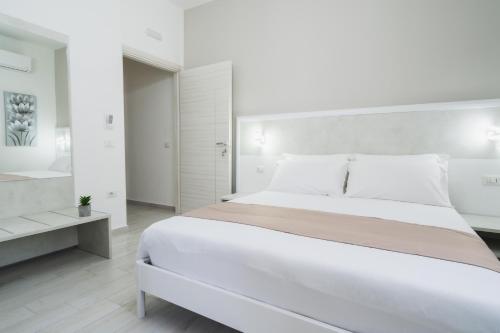 a white bedroom with a large bed and a table at VeMi Affittacamere in Posada
