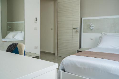 a white bedroom with a bed and a mirror at VeMi Affittacamere in Posada