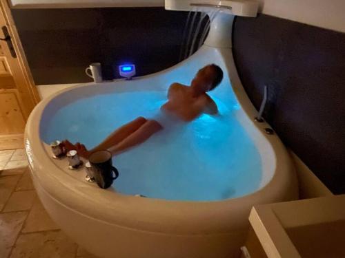 a man in a bath tub in a bathroom with a toilet at Chalet le Vertical - Chalet5*, sauna, jacuzzi, billard, balnéo, massage, pistes à 150 m in Les Deux Alpes