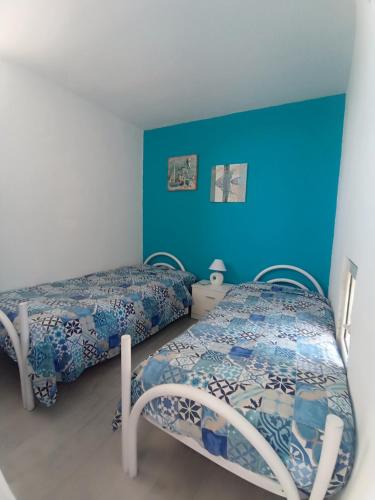 2 camas en una habitación con paredes azules en Casa vacanze bluchic Gioisia, en Isola delle Femmine