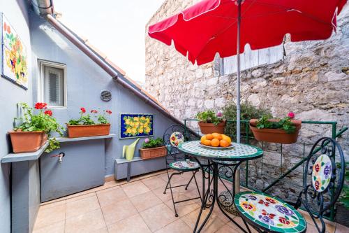 un patio con una mesa con una sombrilla roja en Tulip Old Town, en Dubrovnik