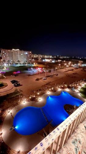 een uitzicht op een strand in de nacht met een blauw zwembad bij العلمين in El Alamein
