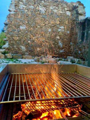 a grill with fire in front of a stone wall at Pool oasis with private parking -Vigia 8 in Torres Vedras