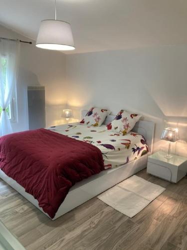 une chambre avec un grand lit avec une couverture rouge dans l'établissement Maison climatisée avec PISCINE CHAUFFEE, à Carlux