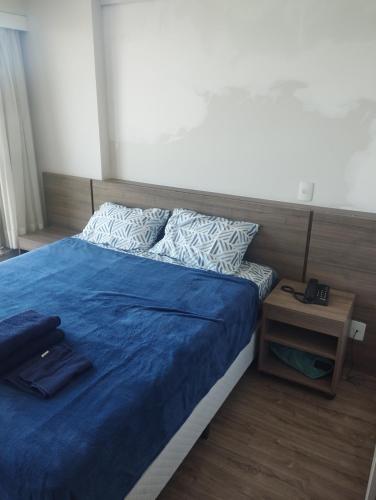 a bedroom with a blue bed and a night stand at Flat Premiere Rio Centro in Rio de Janeiro