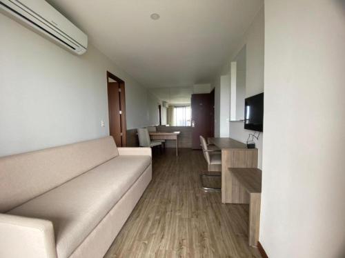 a living room with a white couch and a table at Flat Premiere Rio Centro in Rio de Janeiro