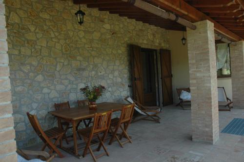a patio with a wooden table and chairs and a stone wall at Agriturismo Tara in Amelia