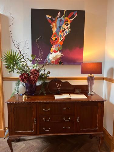 a desk with a painting of a giraffe on the wall at Morven Guest House Carnoustie in Carnoustie