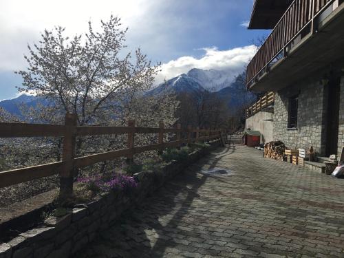 a brick path with a fence and mountains in the background at La casa del bosco in Aosta