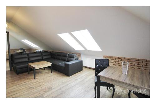 una sala de espera con muebles de cuero negro y una mesa en Apartamenty Piła en Piła