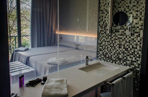 een badkamer met een wastafel en een bed met een spiegel bij Hospedería Valle del Jerte in Jerte