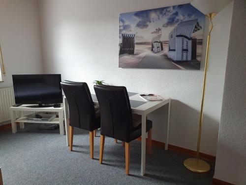einen Schreibtisch mit 3 Stühlen und einen Tisch mit einem TV in der Unterkunft Schöne Doppelzimmer in Rheine