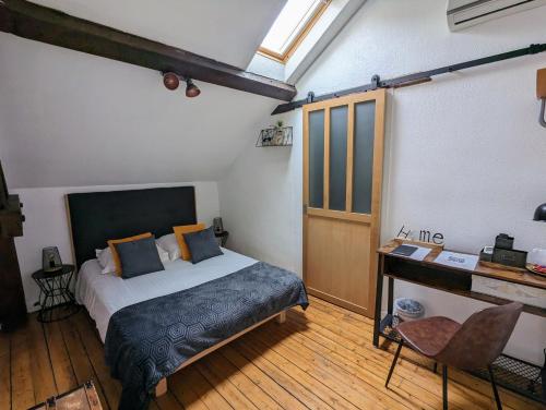 a bedroom with a bed and a desk in a room at Logis Hotel La Tourelle du Beffroi in Bourbon-Lancy