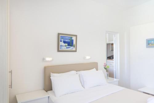 a white bedroom with a bed with white pillows at The Milos in Megalochori