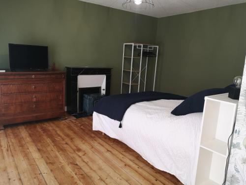 a bedroom with a bed and a dresser and a television at LEBAS-LADIN - Bayeux Ville Touristique in Lison