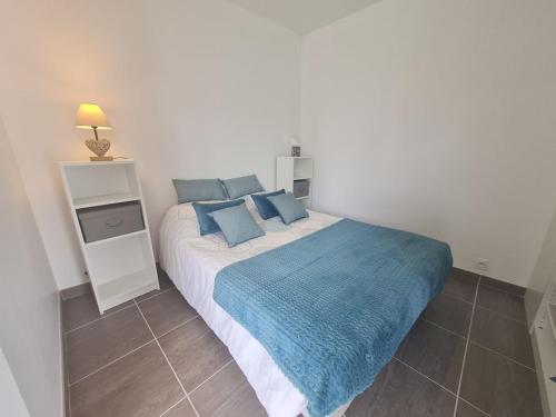 une chambre avec un grand lit avec des oreillers bleus dans l'établissement JOLIE MAISON CHEMIN DES VIGNES, à Saint-Jean-de-Monts