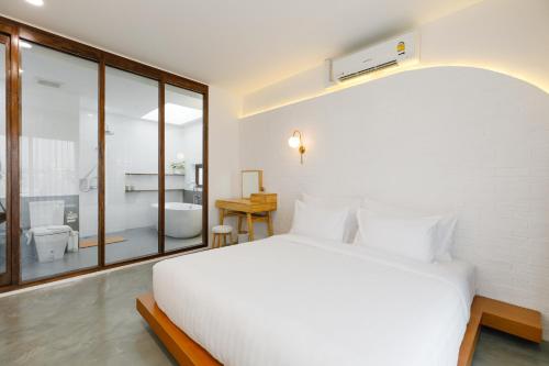 a bedroom with a large white bed and a bathroom at Grow home -Stay and space, Self check-in in Chiang Rai