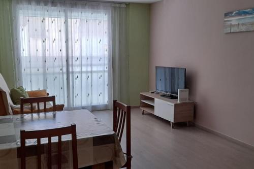 ein Wohnzimmer mit einem Esstisch und einem TV in der Unterkunft Bonito bajo cerca del mar in Benicarló