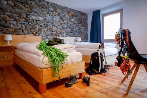 a bedroom with two beds and a stone wall at Bed&Bike Tremola San Gottardo in Airolo