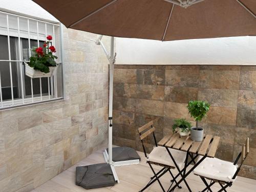 einen Tisch und Stühle mit Sonnenschirm auf einer Terrasse in der Unterkunft Apartamento Los Naranjos de Santa Justa in Sevilla