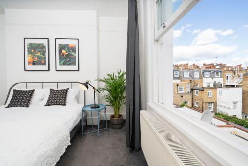 1 dormitorio con cama y ventana grande en Kensington Nest Serviced Town House en Londres