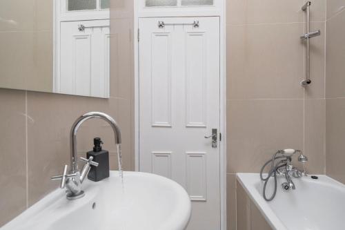 Baño blanco con lavabo y espejo en Kensington Nest Serviced Town House, en Londres