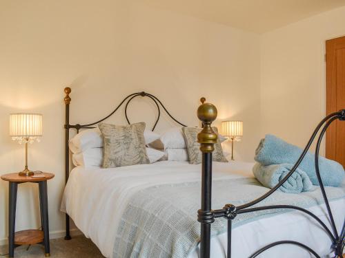 a bedroom with a bed with white sheets and pillows at No 2, The Stables in Southam