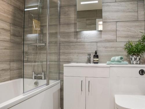 a bathroom with a shower and a sink and a tub at No 2, The Stables in Southam