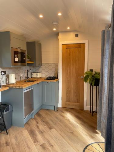 a kitchen with blue cabinets and a wooden floor at Canalside View Mini Lodge with private hot tub in Llangollen