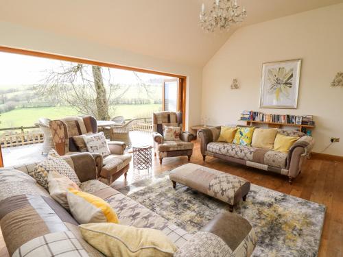 uma sala de estar com sofás e cadeiras e uma grande janela em The Orchard em Knighton