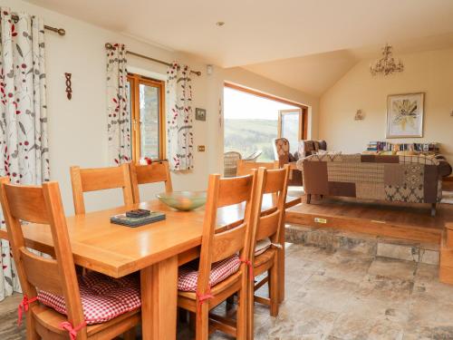 comedor y sala de estar con mesa de madera y sillas en The Orchard, en Knighton