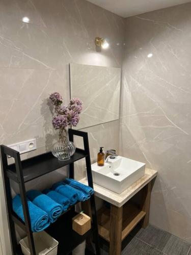 a bathroom with a sink and a vase of purple flowers at Nové bývanie v centre Košíc. in Košice