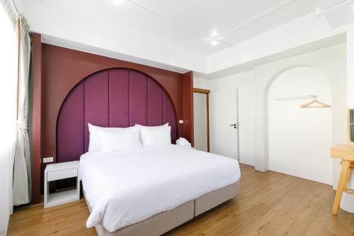 um quarto com uma grande cama branca e uma cabeceira de cama roxa em Grow home -Stay and space, Self check-in em Chiang Rai