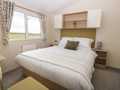 a bedroom with a large white bed with a window at Caravan at Boderw in Holyhead