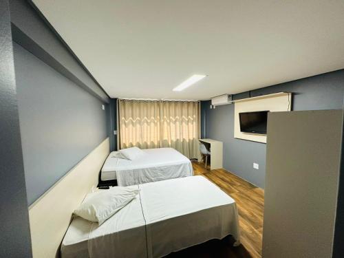 ein Krankenhauszimmer mit 2 Betten und einem TV in der Unterkunft Nacional Hotel Coral in Lages
