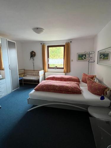 Ferienwohnung Schlossberg 2 في فيرسبرغ: غرفة نوم بسرير ومخدات حمراء ونافذة