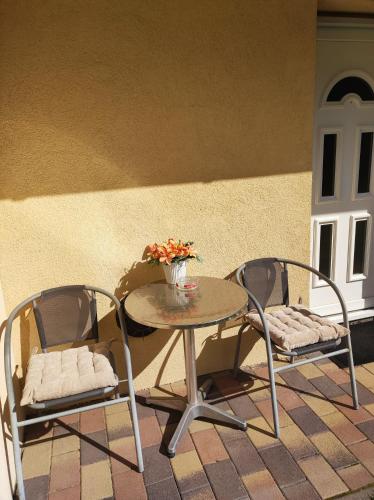a table with two chairs and a vase of flowers on it at Green garden apartment ingyenes zárt parkolóval in Szeged