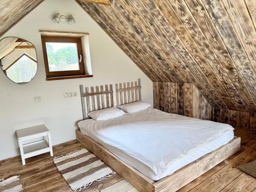 a bedroom with a bed with a wooden ceiling at Dabintos slėnis in Sumiliszki