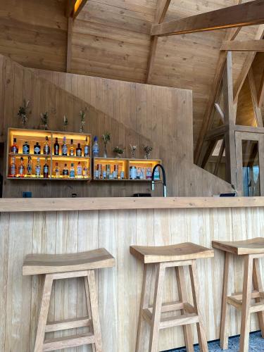 a bar with two wooden stools and a counter at Tawa Refugio del Puelo in Puelo