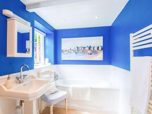 La salle de bains est pourvue d'un lavabo blanc et de murs bleus. dans l'établissement Cuckoo Nod Cottage, à Wool
