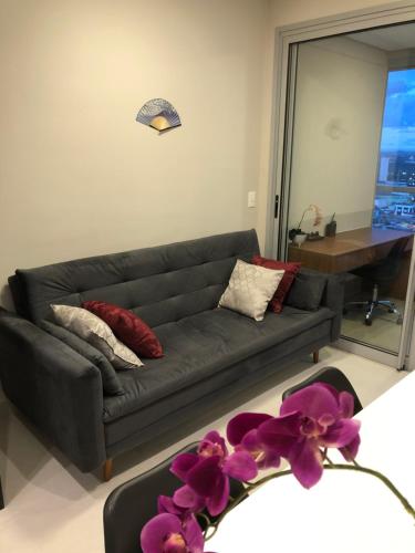a living room with a black couch with purple flowers at Monte Fuji ~ GRU 39m2 in Guarulhos