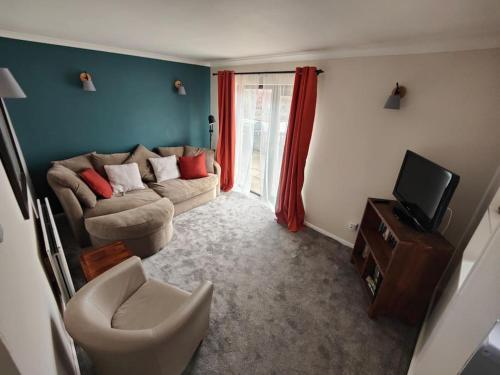 ein Wohnzimmer mit einem Sofa und einem TV in der Unterkunft Newly renovated private Annex by the Sea in Hartley