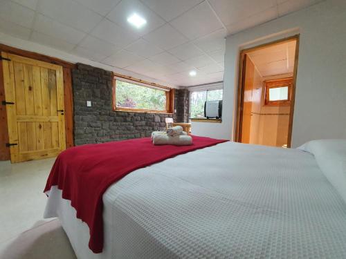 - une chambre avec un grand lit blanc et une couverture rouge dans l'établissement Alquiler cabañas Posada del Angel en Valle Grande, à San Rafael
