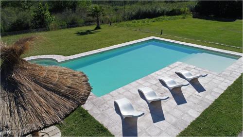 - une piscine avec 2 chaises blanches à côté dans l'établissement Alquiler cabañas Posada del Angel en Valle Grande, à San Rafael
