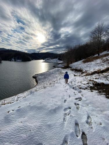 a person walking down a snow covered path next to a body of water at VILA DISHA in Tirana