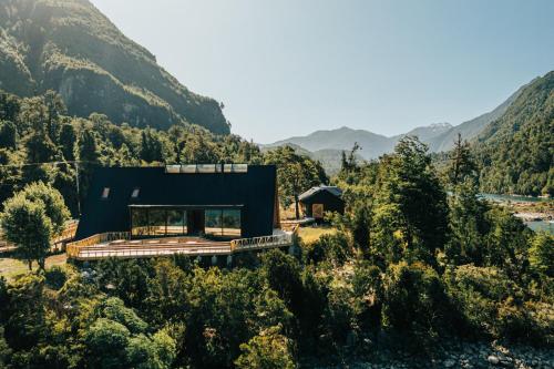 a black house in the middle of a mountain at Tawa Refugio del Puelo in Puelo